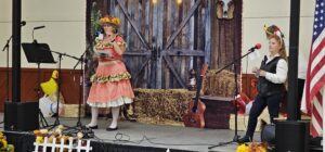 A woman in period dress and a young performer on stage at the OOTFA convention evening show